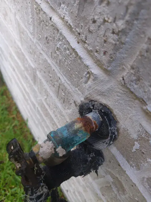 A severely corroded hose bibb on a brick wall in Missouri City